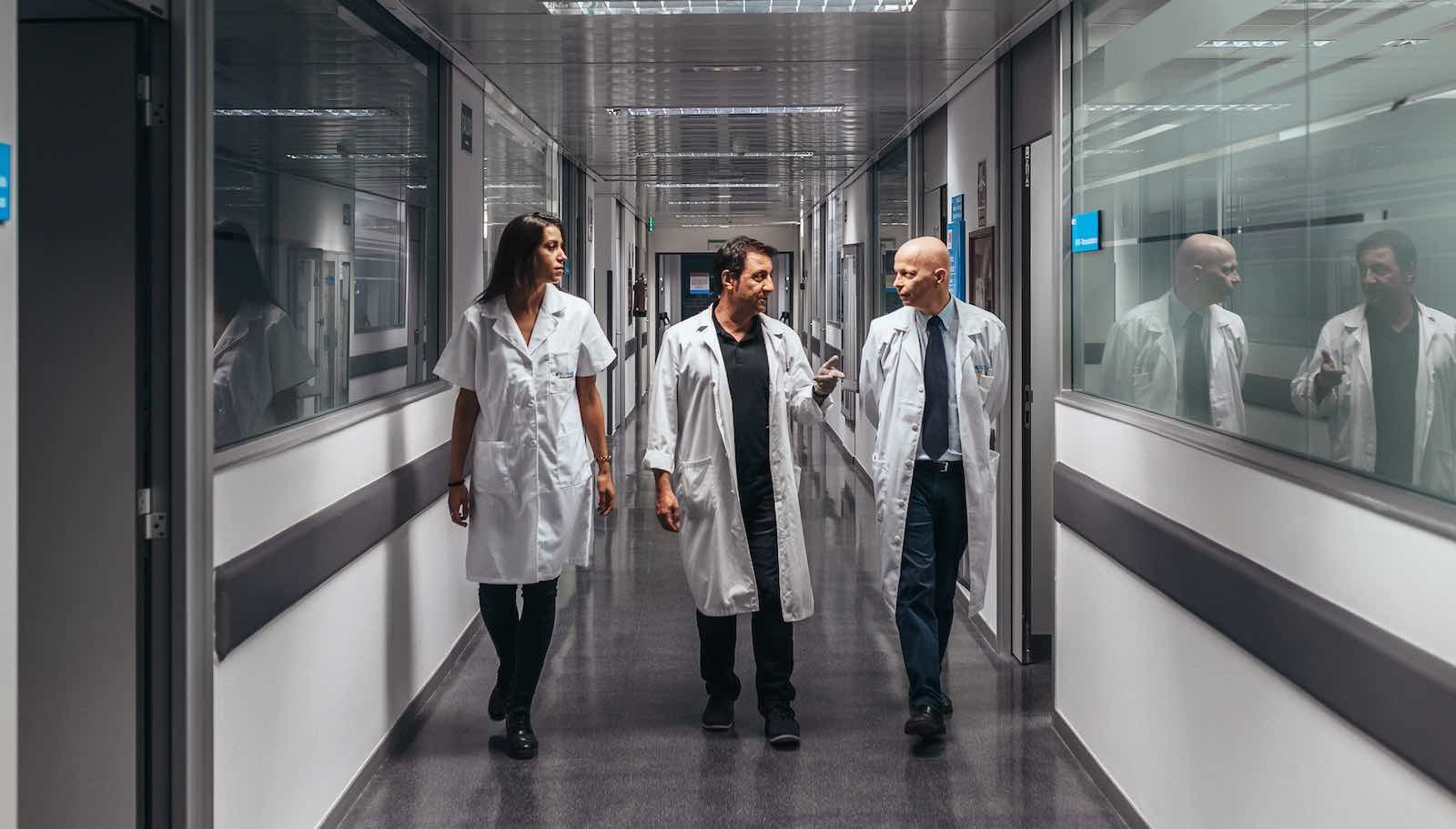 People in white coats walking down a hallway